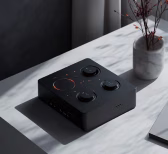 Black modern audio interface device with knobs on a white marble surface beside a plant pot.